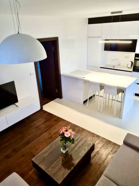 A bright kitchen in a 2-room apartment with a wooden floor, table, and flowers.