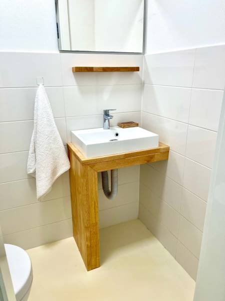 Bathroom with a sink and a wooden cabinet in a 2-room apartment.