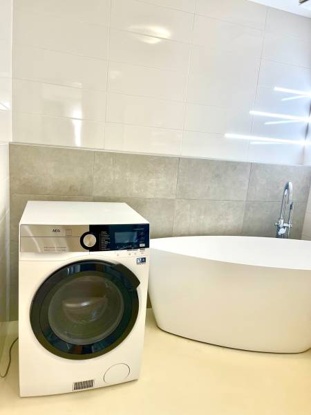 A bathroom with a washing machine and a freestanding bathtub in a two-room apartment.