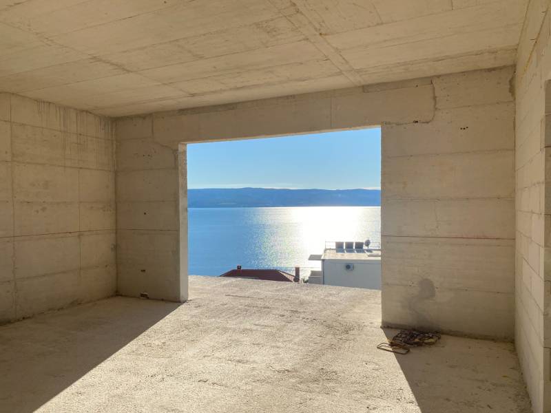An unfinished interior of a villa with a view of the sea and a sunset in the background.