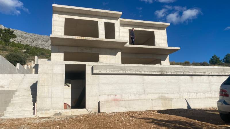 An unfinished villa in Duće against the backdrop of a mountainous landscape.