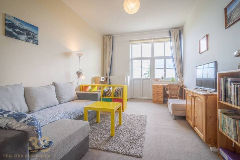 Living room with a light sofa and a yellow table in a 3-room apartment.