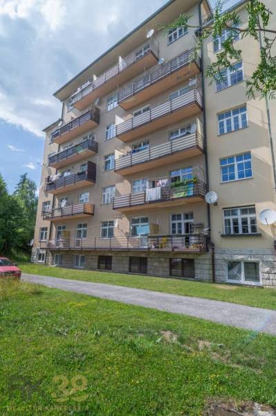 A five-story apartment building in the High Tatras with balconies and a green lawn.