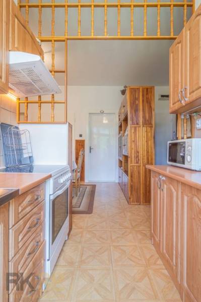A kitchen in a 3-room apartment with a stove, microwave, and wooden cabinets.