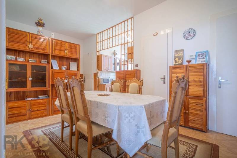 Dining room in a 3-room apartment with wooden furniture and a set table.