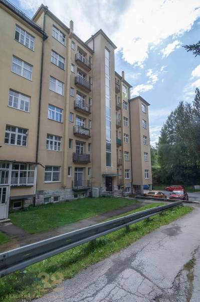 A five-story apartment building in the High Tatras with an access road and parking.