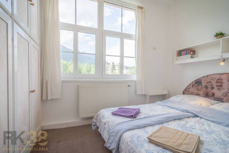 Bedroom in a 3-room apartment with a large window and a view of the mountains.