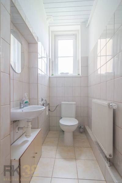 Bathroom in a 3-room apartment with a sink, toilet, radiator, and window.