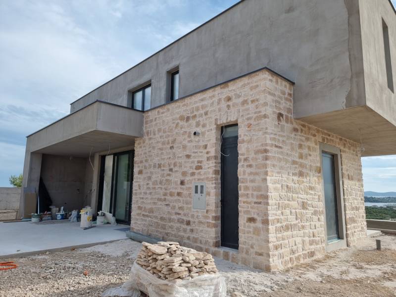 A villa in Vodice with a structured stone cladding and a terrace, nearing completion.