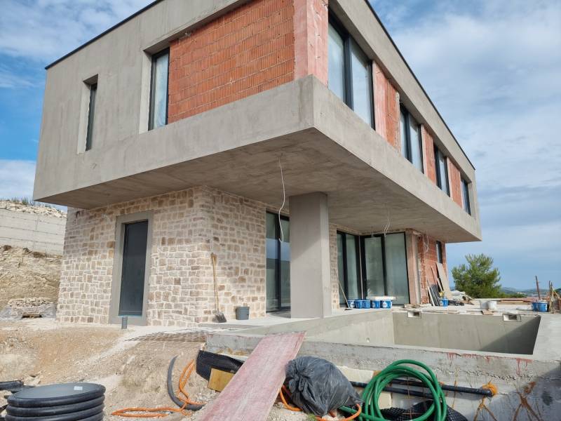An unfinished villa in Vodice with a concrete and brick facade, a swimming pool, and a veranda.