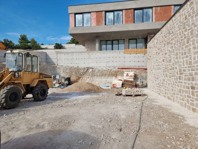 A construction site with a villa under construction in the city of Vodice, visible construction machinery and materials.