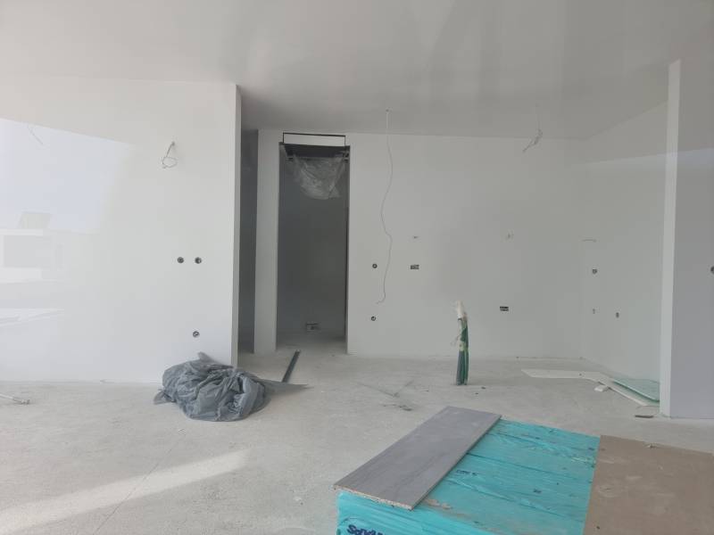 An unfinished room in a villa with white walls and an incomplete floor.
