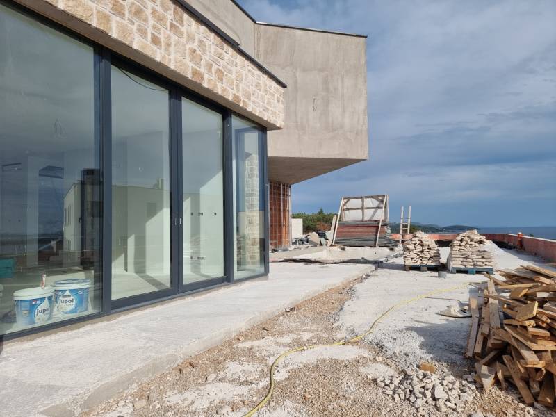 Construction of a villa in Vodice with a glass wall and a construction site on the coast.