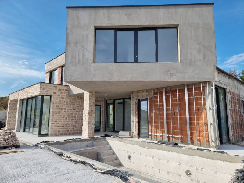 An unfinished villa in the town of Vodice with stone and brick walls, large windows, and a terrace.