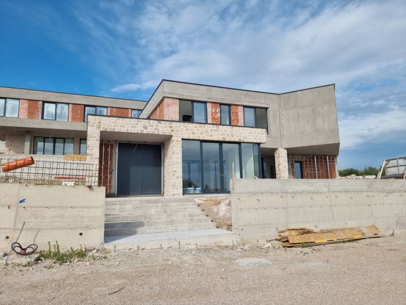 Unfinished villa in Vodice with large glass surfaces and stone cladding.