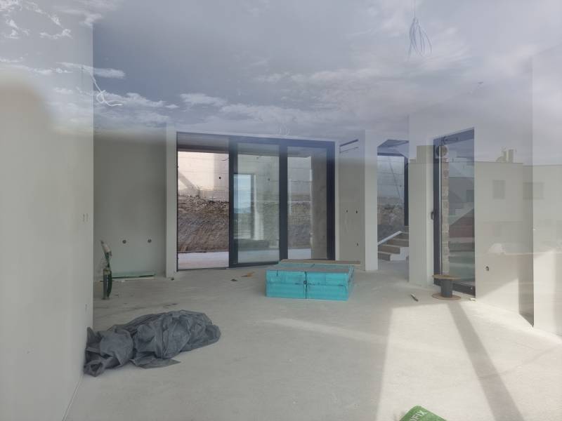 Spacious interior of a villa with large windows and a view of the exterior.