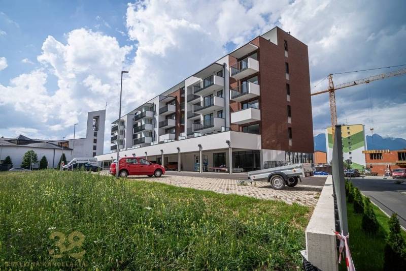 A building in the town of Svit with commercial spaces and a parking lot in the foreground.