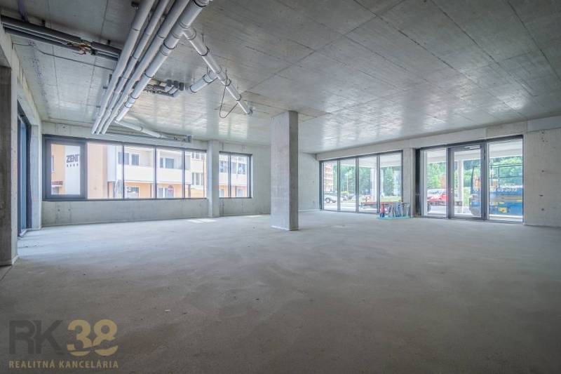Spacious commercial spaces with large windows and raw concrete ceiling.