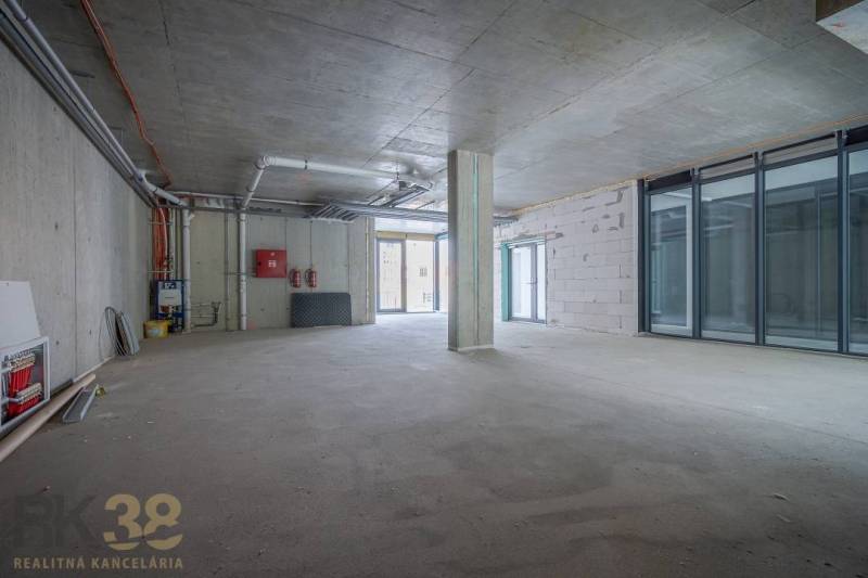 Spacious commercial spaces with concrete walls and large glass doors.