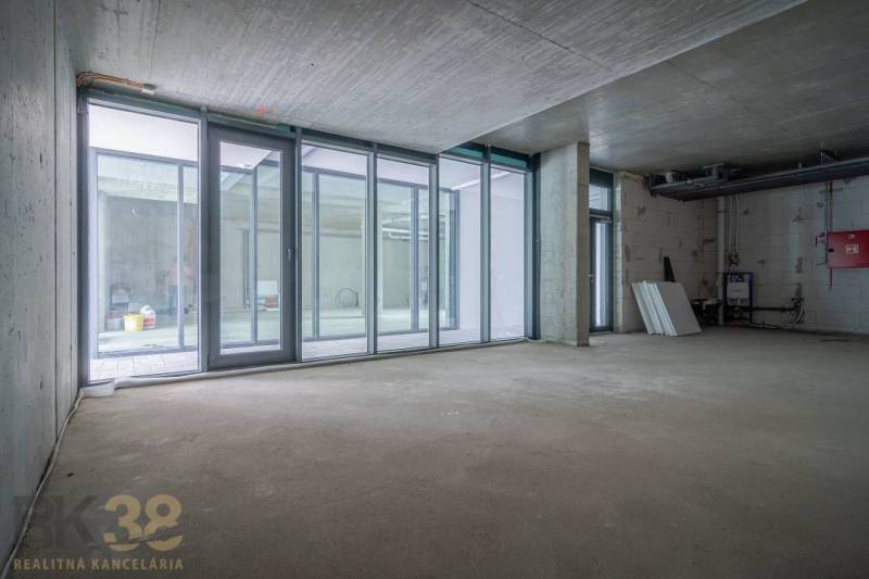 Unfinished commercial spaces with glass walls and a concrete ceiling.
