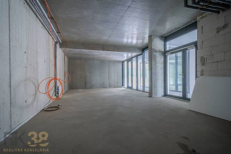 Interior of commercial premises with a glass wall, concrete ceiling, and electrical installation.