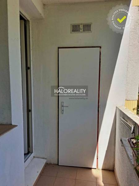 A balcony with white doors in a 3-room apartment, marked by a real estate agency.