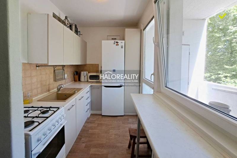 A kitchen in a 3-room apartment with white cabinets, a gas stove, and a window.