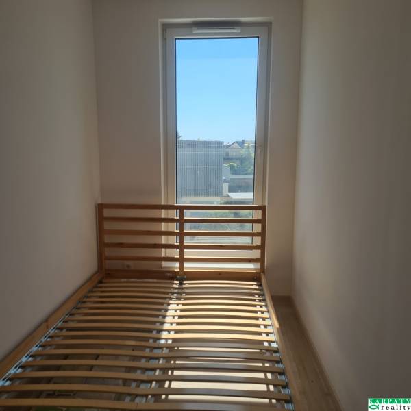 A bright room in a one-bedroom apartment with a bed and a large window.