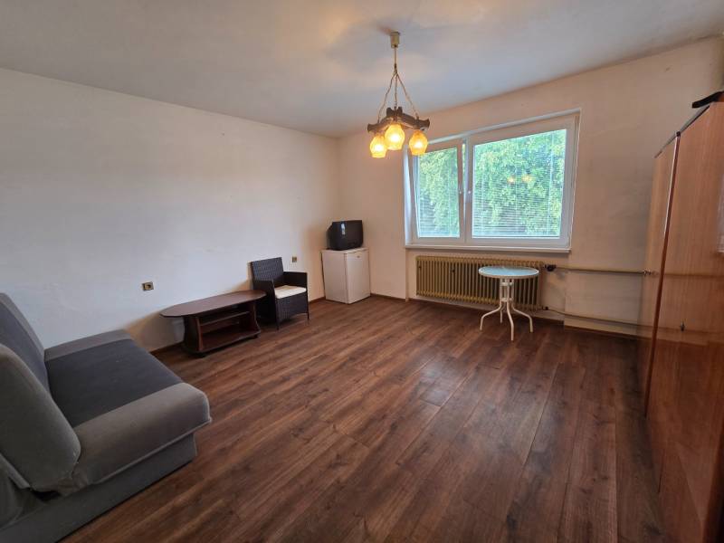 Living room in a family house with wooden flooring, a sofa, and a window.