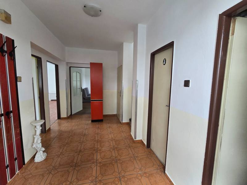 A hallway in a family house with a brown floor, a red wardrobe, white walls.