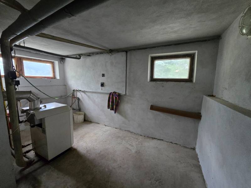 Boiler room in a family house with a boiler, pipes, and small windows.