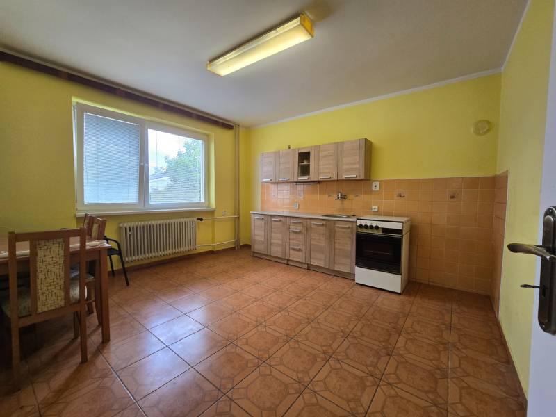 A kitchen in a family house with yellow walls, wooden furniture, and ceramic tiles.