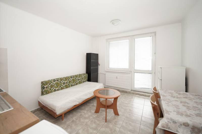 Bright office with a sofa, coffee table, and dining area on a tiled floor.