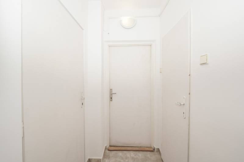 White hallway with closed office doors, a simple space with tiled flooring.