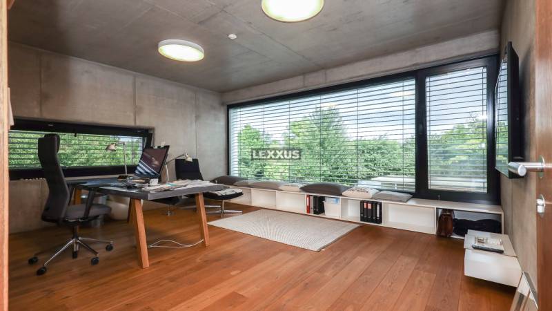 A study in a family house with a large window and wooden floor, modern furniture, view of trees.