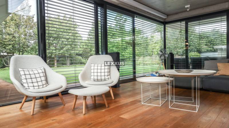 Interior of a family house with comfortable armchairs, wooden flooring, and a view of the garden.