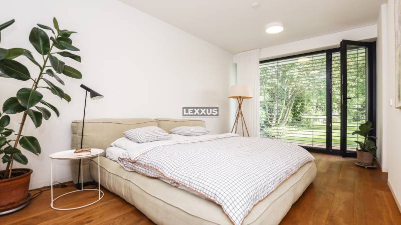 A bedroom in a family house with a bed, plants, and a view of the garden.
