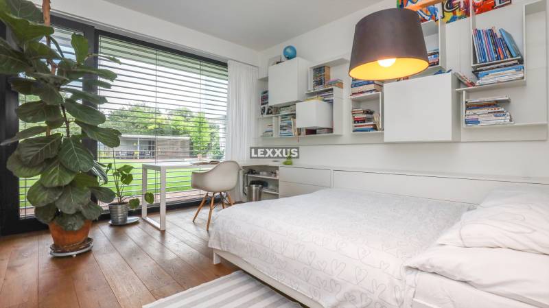 Bedroom in a family house with a bed, shelves, and a large window with a view.