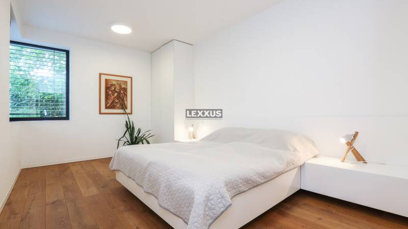 Bedroom in a family house with wooden flooring, a painting, and a nightstand.