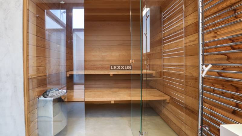 Wooden sauna with glass doors and benches in a family house.