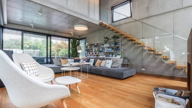 A stylish living room with wooden flooring, a staircase, and large windows in a family house.