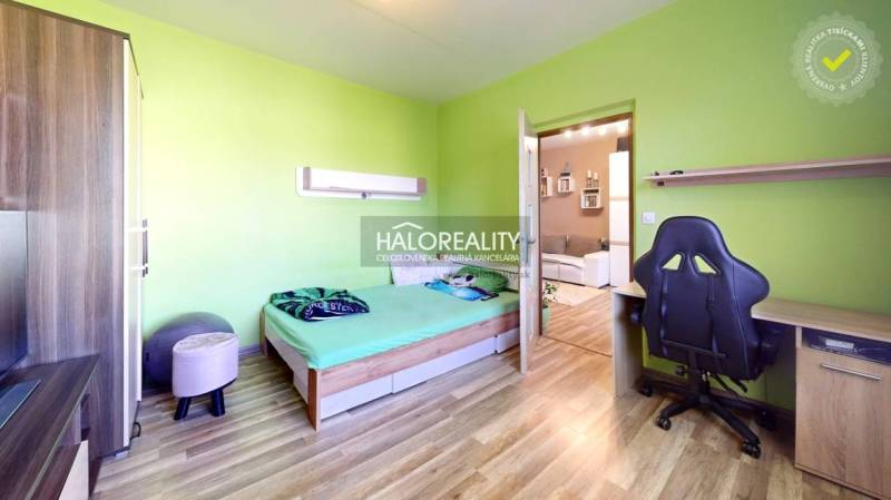 A room in a 2-room apartment with a wooden floor, green walls, and a workspace.