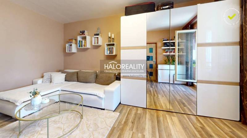 Living room in a 2-room apartment with a white sofa and a mirrored wardrobe.