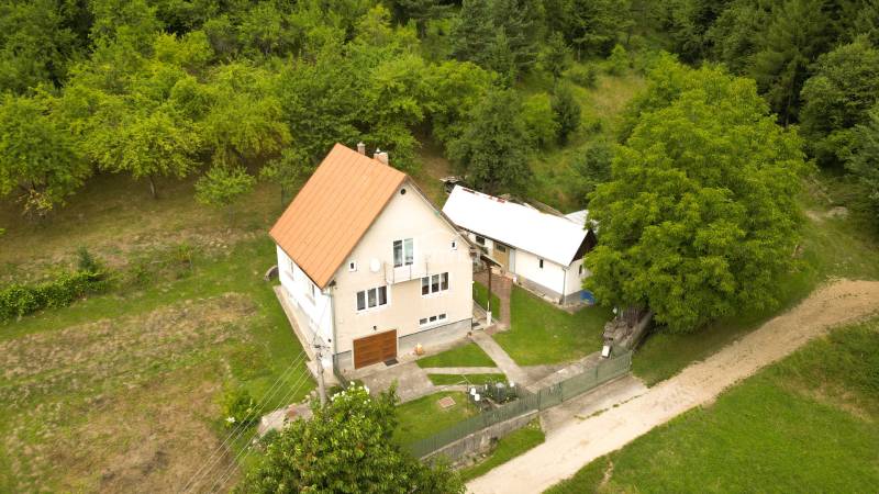 A family house in Papradno surrounded by a grassy plot and trees, access road.