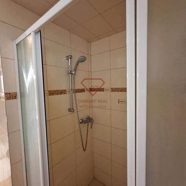 Shower enclosure in a family house with ceramic tiles and an adjustable showerhead.