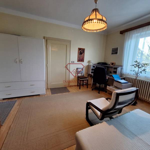 Living room in a family house with an armchair, a desk, and a dresser.