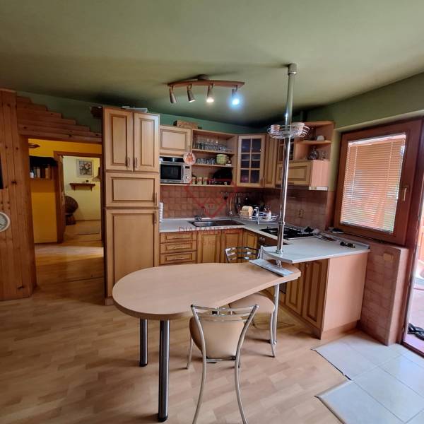 A family house kitchen with wooden furniture, a table, and burgundy walls.