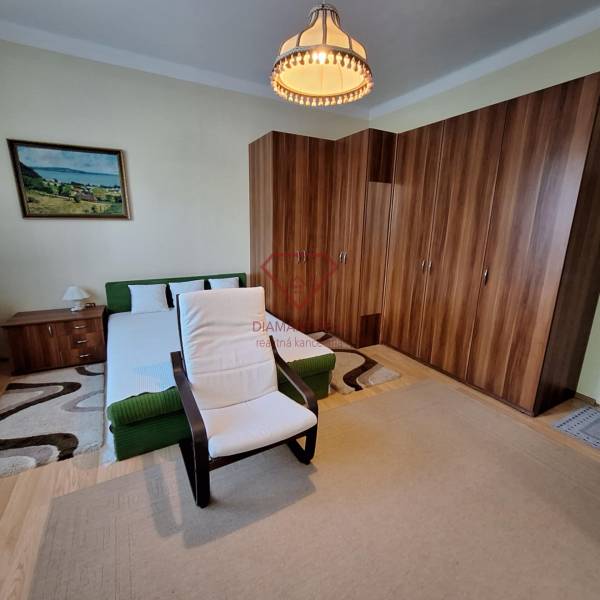 Bedroom in a family house with a bed, an armchair, a large wardrobe, and a painting on the wall.