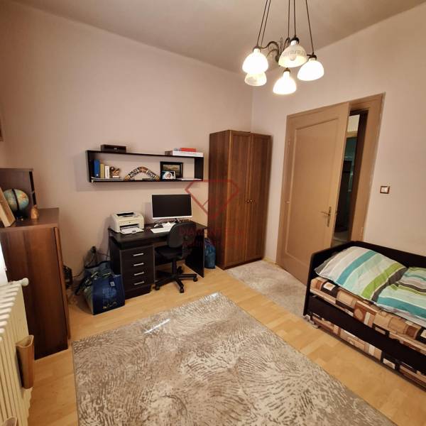 A room in a family house with a desk, a bed, and a wardrobe.