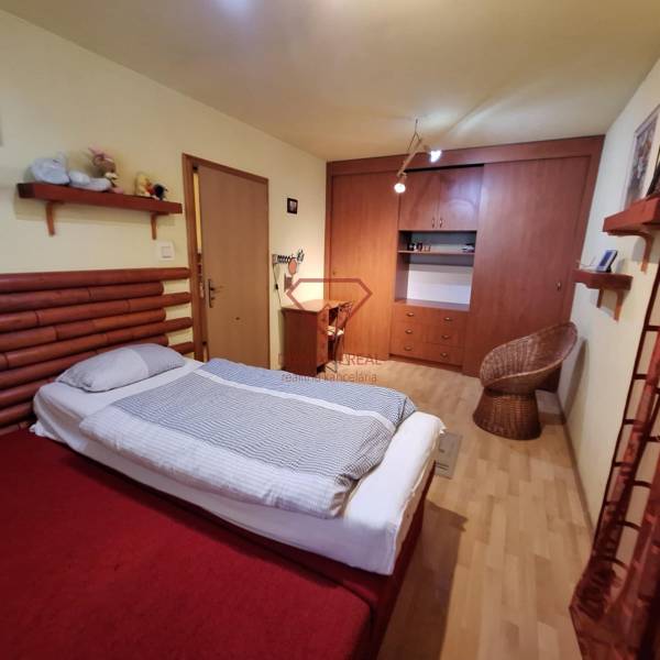 Bedroom of a family house with a bed, wardrobe, and a rattan chair.